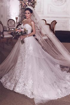 a woman in a white wedding dress standing next to a table with flowers on it