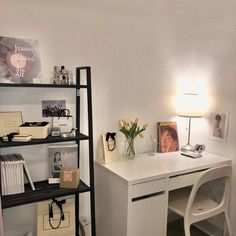 a room with a desk, shelves and pictures on the wall next to a lamp