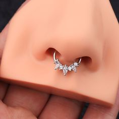 a close up of a person holding a fake nose with an earring on it