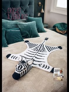 a crocheted zebra rug laying on top of a bed with pillows and blankets