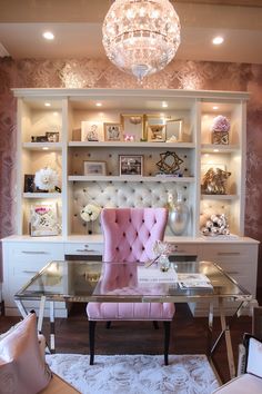 a pink chair sitting in front of a desk with a chandelier above it