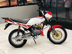 a red and white motorcycle parked in front of a store