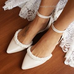 a close up of a person wearing white shoes on a wooden floor with lace around the ankles