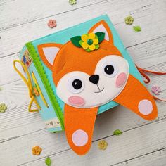 an orange and white stuffed animal sitting on top of a wooden table next to a book