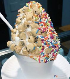 an ice cream sundae with sprinkles and cookies on top is sitting on a white plate