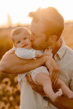 a man holding a baby in his arms while the sun shines down on him