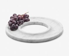 a marble plate with grapes on it and a white ring around the edge that is shaped to look like a circle