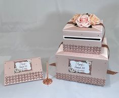 three pink boxes are stacked on top of each other, one has a rose in it