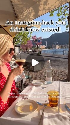 a woman sitting at an outdoor table drinking wine