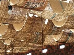 the ceiling is covered with woven material and lights are hanging from it's sides