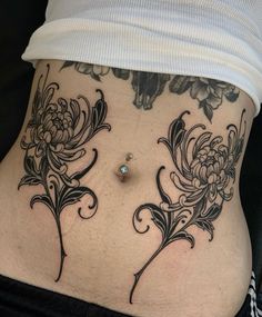 a woman's lower back tattoo with flowers and leaves on her stomach, showing the side