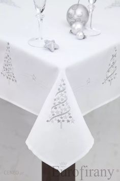 a white table cloth with silver ornaments on it and wine glasses in the center,