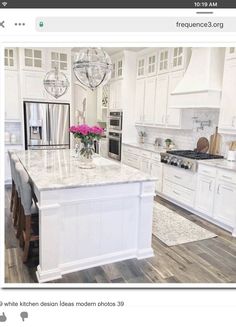 a large kitchen with white cabinets and marble counter tops, an island in the middle