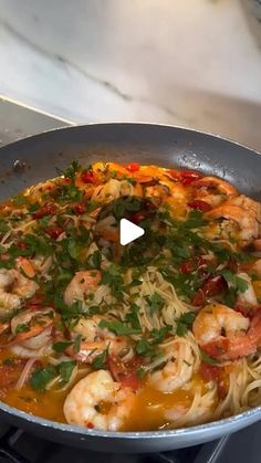 a pan filled with shrimp and noodles on top of a stove