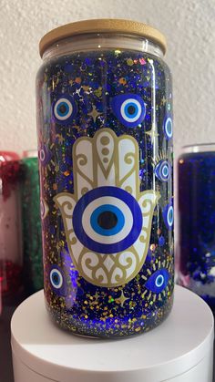 a glass jar with an evil eye painted on the front and side, sitting on top of a table