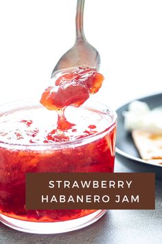 strawberry habanero jam is being poured into a glass jar with a spoon on the side