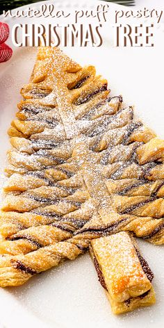 a pastry shaped like a christmas tree on a white plate next to a red ribbon