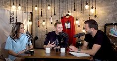 three people sitting at a table with microphones in front of them