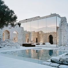 the reflection of an old building in a mirrored wall reflects its surroundings and surrounding stone structures