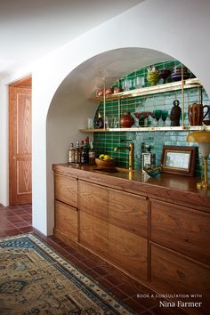 a kitchen with wooden cabinets and green tile backsplash, along with an area rug on the floor