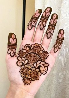 a hand with henna tattoos on it and some flowers in the middle of it