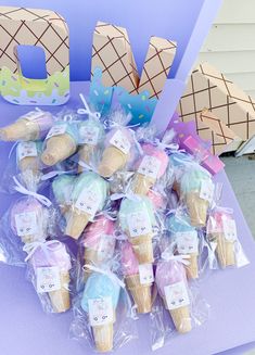 ice cream cones are wrapped in plastic and placed on a purple table with the word love spelled out