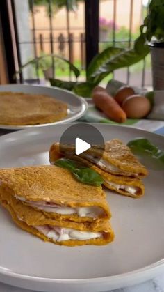 two plates with food on them sitting on a table next to some eggs and vegetables