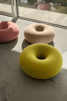 three different colored donuts sitting next to each other on the floor in front of a window