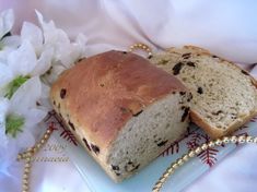 a loaf of bread sitting on top of a white plate next to a bouquet of flowers