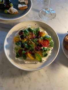 two plates with food on them sitting on a table next to wine glasses and utensils