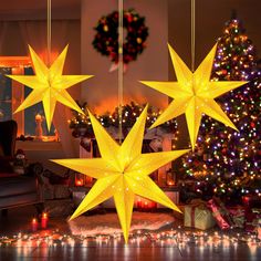 three yellow stars hanging from the ceiling in front of a christmas tree and other decorations