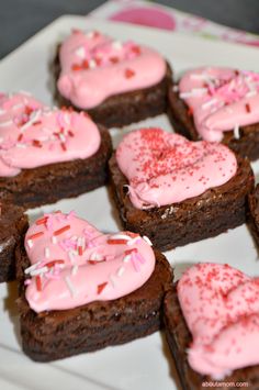 chocolate brownies with pink frosting and sprinkles on a white plate