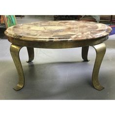 a coffee table with marble top sitting in a room next to other tables and chairs