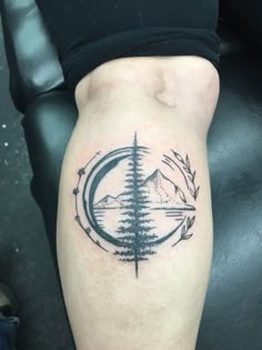 a tattoo on the leg of a person with trees and mountains in the background,