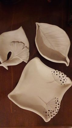 three white dishes with designs on them sitting on a wooden table next to an empty plate