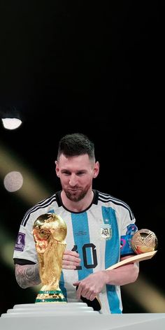 a man holding a golden trophy in his right hand and wearing a blue and white shirt