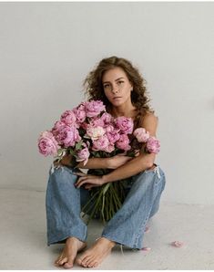 a woman sitting on the floor with flowers in her lap