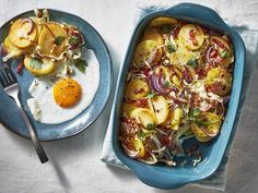 an egg and potatoes dish in a blue casserole dish on a white tablecloth