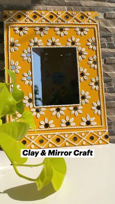 a yellow and white mirror sitting on top of a table next to a green plant