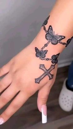 a woman's hand with a cross and butterflies tattoo on it