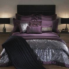 a bed with purple and silver sequins on the comforter, pillows and blankets