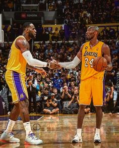 two basketball players shaking hands in front of an arena full of people with fans watching