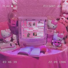 a laptop computer sitting on top of a pink table covered in stuffed animals and books