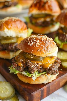 hamburgers with pickles and cheese on a cutting board