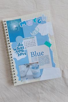 a spiral notebook with blue images and words on the cover is laying on a bed