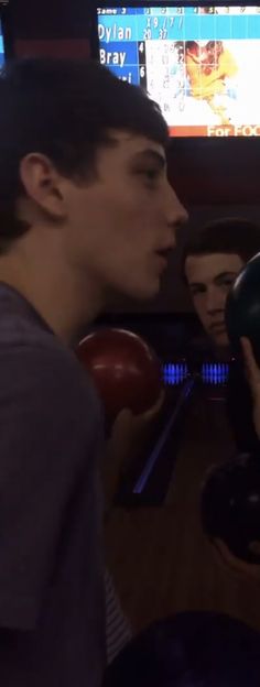 a man holding a bowling ball in his right hand and looking at another person's face