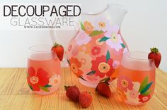 a pitcher and two glasses with strawberries on the table next to it that is shaped like flowers