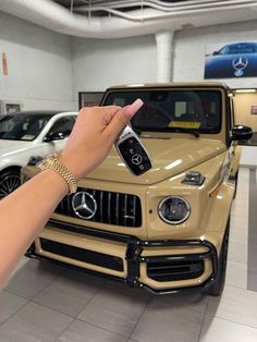 a hand holding a remote control in front of a mercedes benz truck at a dealership