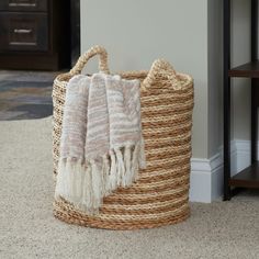 a basket that has some towels in it next to a table with a vase on it