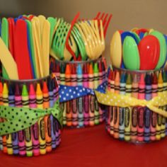 colorful plastic utensils and spoons in cups on a table